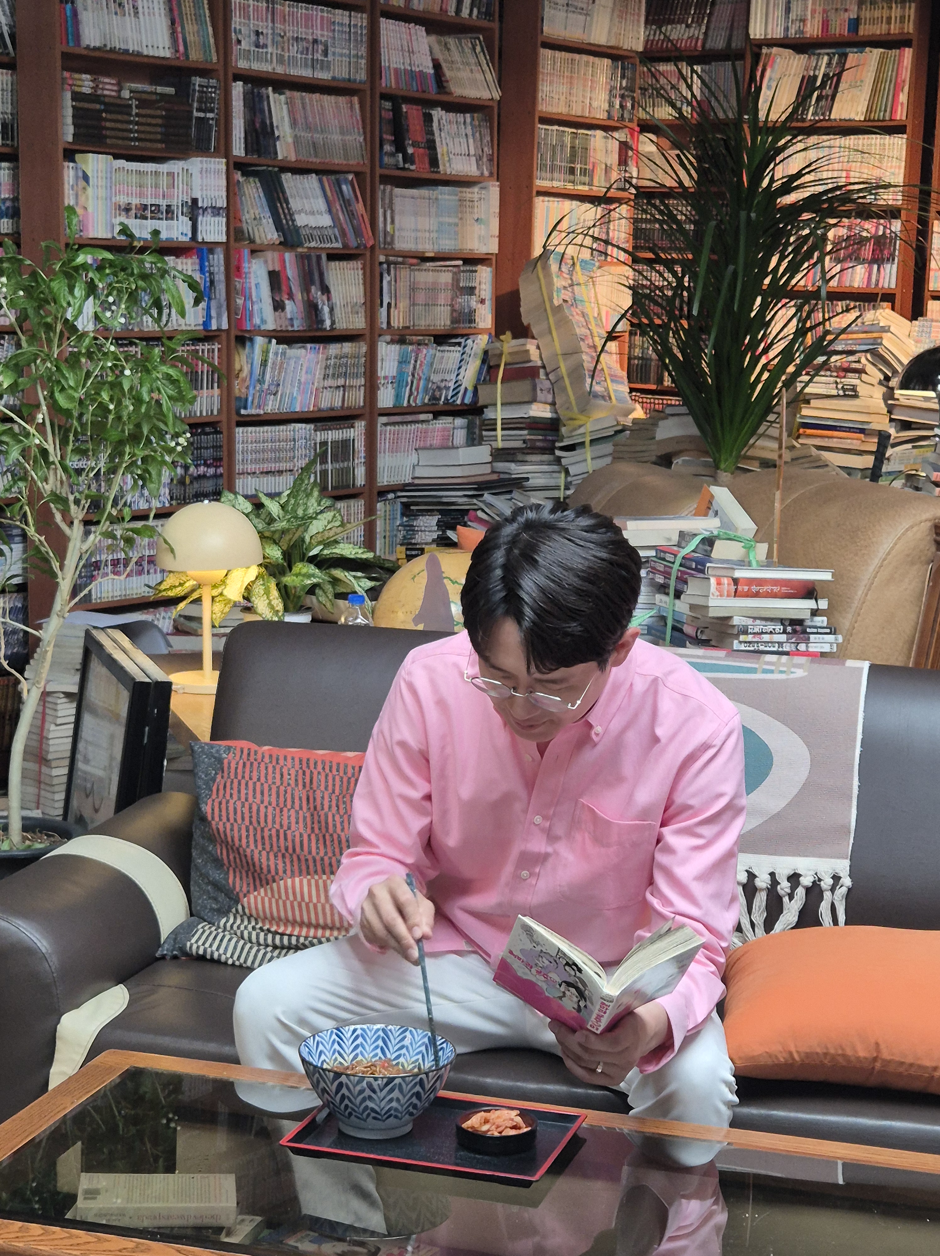 만화방 소파에서 만화책과 라면을 즐기는 모습