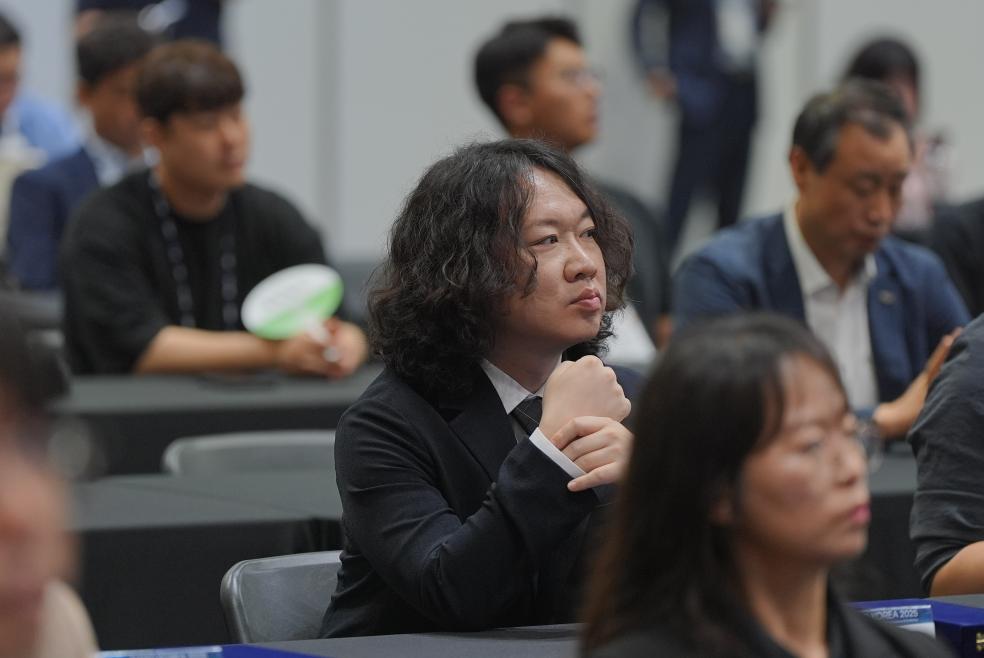 정장을 입고 시상식 객석에 앉아 있는 모습
