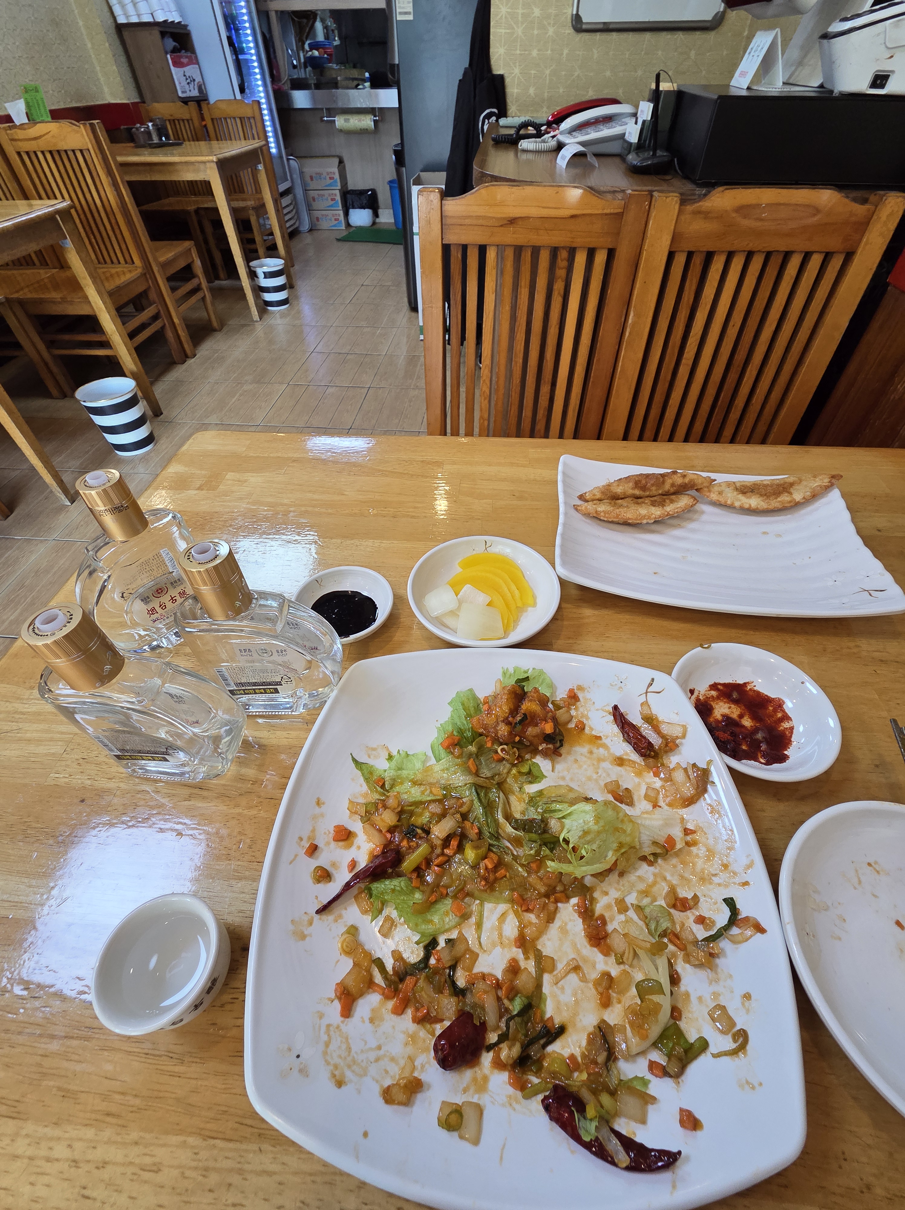 식사를 마친 깐풍기 접시와 연태고량주 세 병